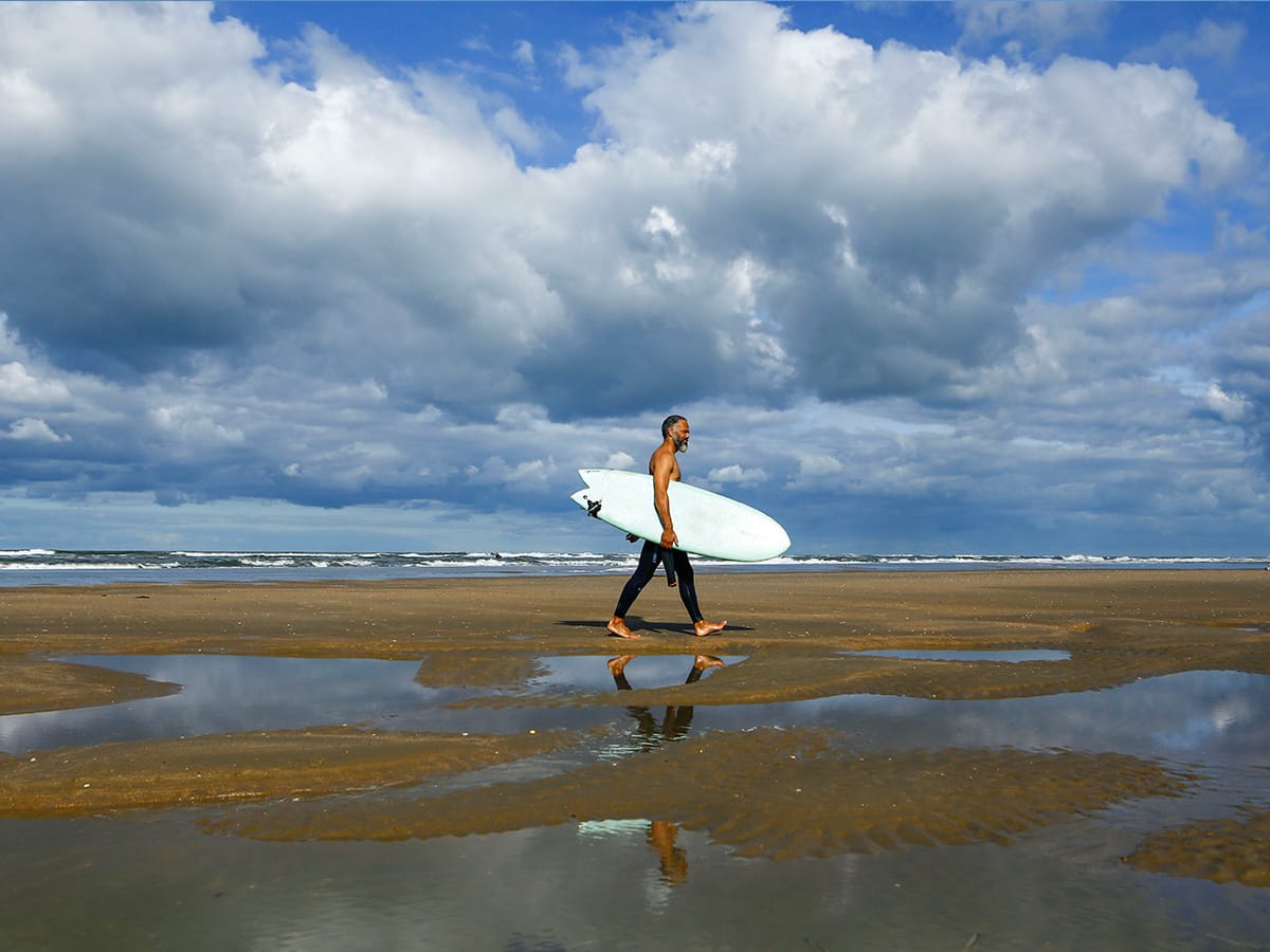 Surfer loopt over het strand