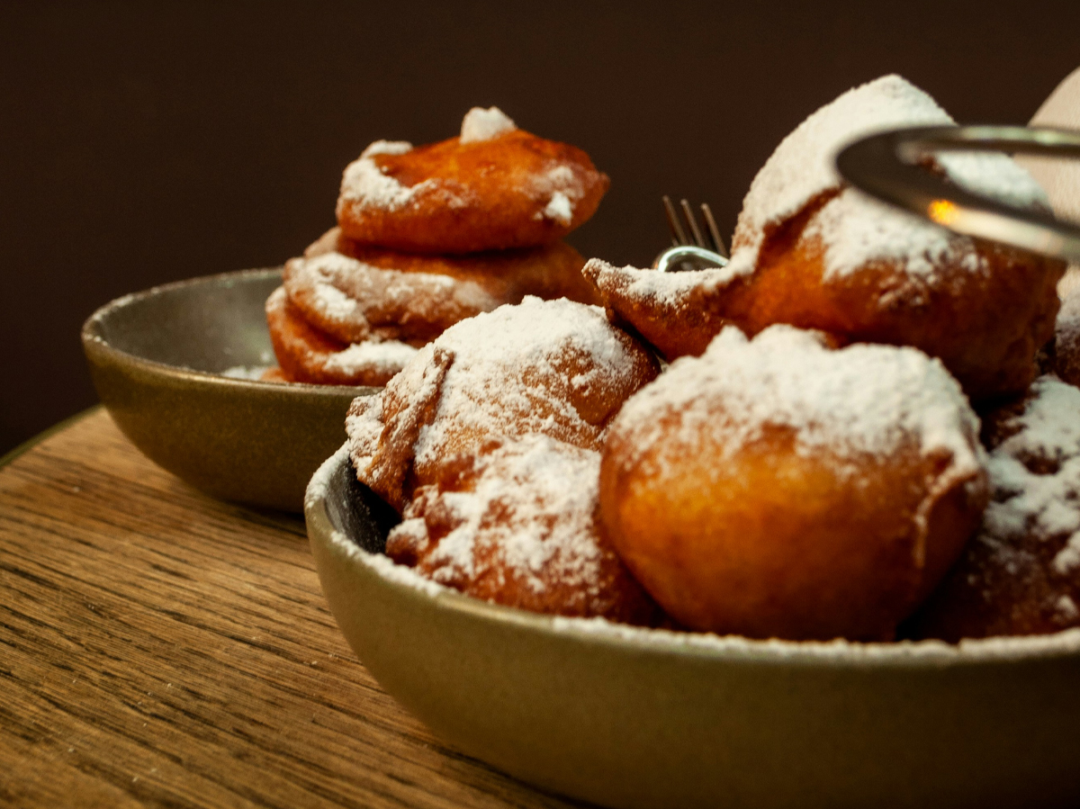 Een schaal met oliebollen met poedersuiker