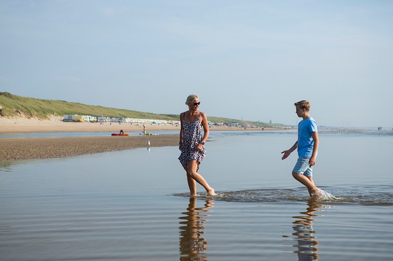 Moeder en zoon in het water op het strand van Castricum